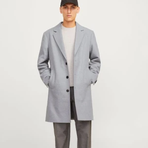 Grå rock från Jack & Jones, storlek M - Snygg grå rock från Jack & Jones med klassisk krage och tre svarta knappar framtill. Jackan har två sidofickor och är helfodrad med svart innerfoder. Perfekt för dig som gillar stilren och enkel design. ANVÄNT ENDAST EN GÅNG!!! Ordpris 1500kr 