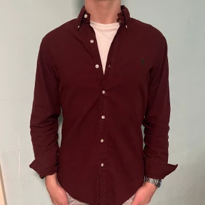Ralph Lauren skjorta Vinröd - Säljer denna stilrena och snygga vinröda  Ralph Lauren skjorta. Skjortan är i mycket bra skick. Modellen är M slim fit. Har du några frågor? Tveka inte att höra av dig. Allt gott från Deluxe garderoben ⭐️