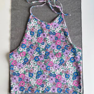 Blommig topp från Bik Bok - Säljer en färgglad topp från Bik Bok i storlek S. Toppen har ett blommigt mönster med vita detaljer. Den är ärmlös och har knyt i nacken. Aldrig använd.