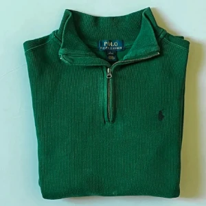 Grön stickad tröja Polo Ralph Lauren - Snygg grön stickad tröja från Polo Ralph Lauren med half zip och hög krage. Klassisk broderad logga på bröstet. Perfekt för lager-på-lager och chill stil. Passar både till jeans och chinos.
