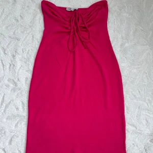 Rosa kort klänning från Zara (Strl S) - Supersnygg rosa klänning från Zara med snörning framtill och axelbandslös design. Klänningen är figurnära och har en kort längd. Skriv om flera bilder önskas 🥰