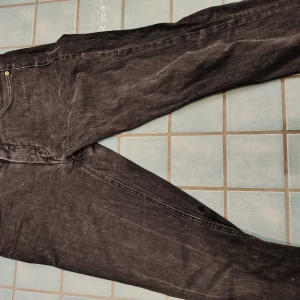 ACNE designerjeans svart/grå 30/32 - Säljer ett par svarta jeans från Acne Studios med klassisk femficksdesign och guldfärgade nitar. Jeansen har raka ben och normal passform, tillverkade i mjukt denimtyg. Perfekta för dig som gillar stilrena och tidlösa plagg.