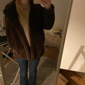 Brun pälsjacka från H&M Divided - Mysig brun pälsjacka från H&M Divided med oversized passform och stora slag. Jackan är helfärgad och har ett fluffigt och mjukt material. Perfekt för kalla dagar när du vill vara både varm och snygg.
