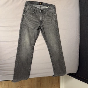 Grå Lee Daren Zip Fly jeans W28 L32 - Snygga grå jeans från Lee i modellen Daren Zip Fly. Jeansen har klassisk femficksdesign, dragkedjegylf och är tillverkade i bomull. De har en rak passform och Lee-logga på bakfickan. Perfekta för dig som gillar en stilren look.