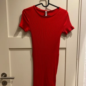 Röd ribbad kortklänning från H&M Divided - Säljer en röd ribbad kortklänning från H&M Divided i storlek S. Klänningen har rund halsringning och korta ärmar, med en tight passform och vertikala ribbade detaljer som ger en snygg struktur. Perfekt för dig som gillar enkel och stilren design.