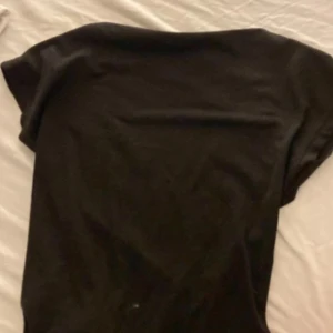 Svart topp med öppen rygg - Säljer en svart topp med korta ärmar och snygg öppen rygg. Enkel och stilren design som passar perfekt till jeans eller kjol. Mjuk och skön känsla, troligtvis i bomull eller polyester. Perfekt för dig som gillar minimalistisk stil.