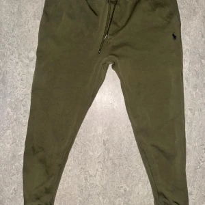 Olivgröna mjukisbyxor Polo Ralph Lauren - KAN GÅ NER I SNABBT KÖP Olivgröna mjukisbyxor från Polo Ralph Lauren med klassisk broderad logga på höften. Byxorna har snörning i midjan och är tillverkade i mjuk bomull. Perfekta för chill dagar eller när du vill vara bekväm men ändå se snygg ut. 