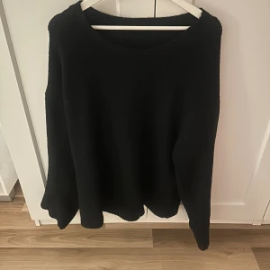Svart stickad tröja från BikBok - En svart stickad tröja från BikBok i storlek L. Tröjan har en enkel och clean design med rund halsringning och långa ärmar. Perfekt för lager-på-lager och chill dagar. Mjuk och skön att bära. Stor i storleken, passar även XL