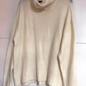 stickad polotröja - Mysig krämvit stickad polotröja med bred polokrage och långa ärmar. Tröjan har en relaxed fit och ribbade muddar vid ärmslut och nederkant. Perfekt för kyliga dagar när du vill vara både varm och snygg.