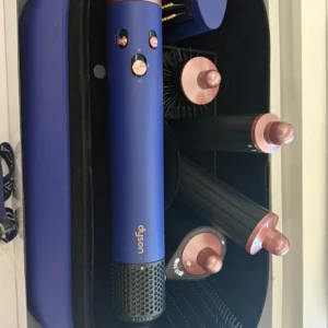 Dyson Airwrap Multi-Styler - Dyson Airwrap Multi-Styler med flera stylingtillbehör i olika färger. Komplett set med borstar och locktillbehör, perfekt för att skapa olika frisyrer. Produkterna ser välvårdade ut, vissa i nyskick med originalförpackning. Ingen synlig skada eller slitage.