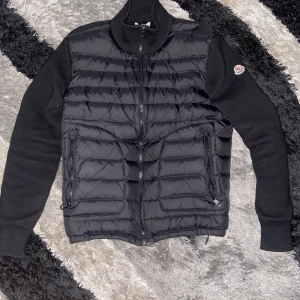 Svart Moncler cardigan  -  Säljer min Moncler cardigan i storlek XS, använd endast 3 gånger, så den är i nästan nyskick. Otroligt fin passform och klassisk Moncler-kvalitet — både bekväm och exklusiv. Passar perfekt nu till hösten/vintern,