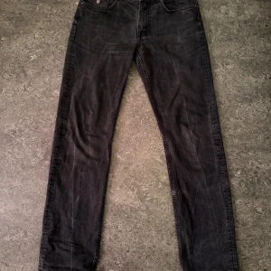 Svarta jeans från GANT - Säljer ett par svarta jeans från GANT med klassisk femficksdesign och broderad logga på myntfickan. Jeansen har raka ben och är tillverkade i mjukt denimtyg som sitter snyggt. Perfekta för dig som gillar stilrena och tidlösa jeans.