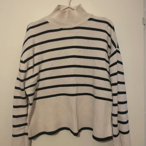 Randig polotröja från Gina Tricot XS - Stickad tröja, beige och svart randig med slit nertill. 