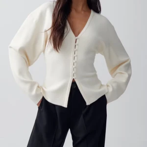 Beige kofta med v-ringning från Gina Tricot - Supersnygg beige kofta från Gina Tricot med v-ringad hals och dekorativa knappar framtill. Modellen är lite loose och har långa ärmar. Perfekt att slänga på sig när du vill ha en chill men stilren look. Materialet är mjukt och känns skönt mot huden, Helt slut såld i storlekar. 