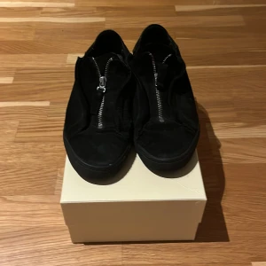 Svarta axel arigato mockasneakers med dragkedja - Säljer ett par svarta sneakers från Axel arigato med några defekter. Mitt pris 400kr nypris: 2000kr box medföljer 