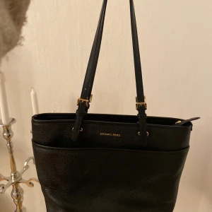 Svart axelväska från Michael Kors -  svart axelväska från Michael Kors med guldfärgade detaljer och justerbara axelremmar. Har bara använt max 3 gånger. Priset kan diskuteras 🥰