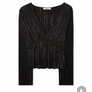 Svart plisserad topp från NA-KD - Säljer en svart  topp från NA-KD i st S med v-ringning och långa ärmar. Toppen har en glansig finish och är croppad i modellen, vilket ger en trendig look. Perfekt för dig som vill sticka ut med stilrena detaljer.