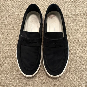 Svarta mockaloafers från Marco Tozzi - Svarta loafers från Marco Tozzi i mjuk mocka med klassisk pennyloafers-look. Riktigt stilrena skor i bra skick. Storlek 44. Tveka inte att höra va sig vid frågor! Priset ej hugget i sten!