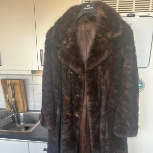 Mörkbrun pälsjacka med bred krage - Säljer en lång, mörkbrun mink pälsjacka med bred krage och  knappar framtill. Vintage 