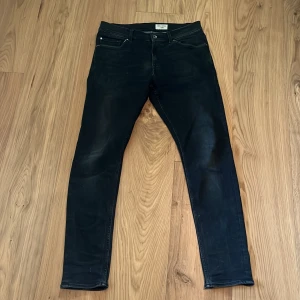 Svarta skinny jeans Tiger of Sweden - Svarta jeans från Tiger of Sweden i modellen 'Evolve'. Snygg, smal passform med klassisk femficksdesign och diskreta sömmar. Jeansen är tillverkade i stretchig bomullsmix för en bekväm känsla och sitter tight hela vägen ner.