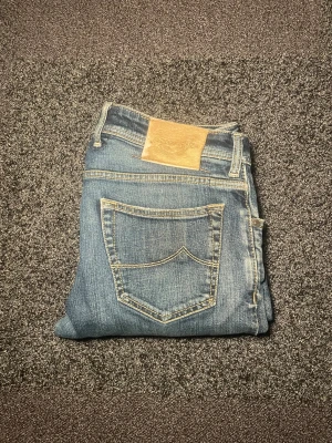 Jacob Cohen jeans - Snygga blå jeans från Jacob Cohen med klassisk femficksdesign och ljusa slitningar på låren i storlek w34, mycket bra skick!