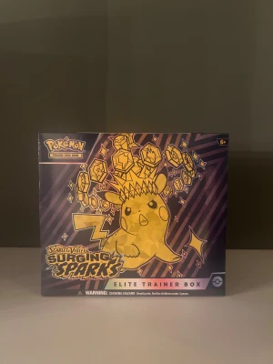 Pokémon Surging Sparks ETB – Oöppnad & Sealad - Säljer en Pokémon TCG Surging Sparks Elite Trainer Box – helt oöppnad, fabriks-sealad och i perfekt samlarskick. Innehåller boosters, sleeves, tärningar, manual och allt som ingår i en ETB  Fraktas tryggt och säkert så inget kommer till skada.