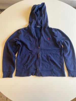 Zip up Ralph lauren - Säljer en Mörkblå zip up från Ralph lauren. Har en fläck på vänstra fickan och dragkedjan saknar en del som ni ser på bilderna. Strl XS. Hör gärna av er om ni har några frågor! MVH tom