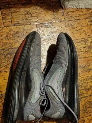 Nike Air Max 720 grå sneakers str 47 - Nike Air Max 720 sneakers i grå mesh med svarta och orange detaljer. Snygg vågig design på ovandelen, synlig Air Max-sula och snörning. Storlek 47! Knappt använda men ej Perfekt skick. 