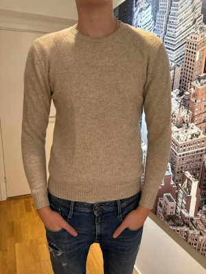 Beige stickad tröja från John Henric - Snygg beige stickad tröja från John Henric i storlek M. Tröjan är använd varsamt och är väldigt bra skick utan några defekter, lite nopprig men går lätt att ta bort.