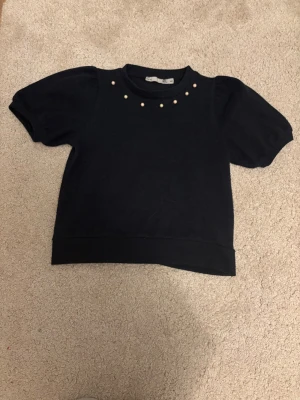 Marinblå T-shirt med puffärmar med pärlor tröja från lager från 157 - Marinblå kortärmad topp från 157 med puffärmar. Om sytt plagg till en finare modell. Pärlor ej på baksida