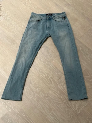 Replay Rocco ljusblå jeans comfort fit - Säljer ett par Replay Rocco jeans i ljusblå tvätt med comfort fit. Klassisk femficksmodell, raka ben och normal passform. Jeansen har snygga detaljer vid fickorna och ett brunt Replay-märke bak i midjan. Perfekt för dig som gillar stilrena och bekväma jeans.
