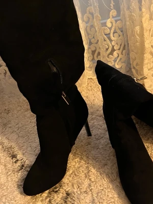 Svarta stövletter från River Island - Säljer ett par svarta stövletter från River Island i storlek 38. De har spetsig tå, hög klack och platåsula. Materialet är mocka och de har dragkedja på sidan för enkel påtagning. De är knappt använda och i nytt skick.🌸 