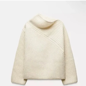 Beige stickad polotröja med ribbad krage - Säljer en beige stickad polotröja med bred, ribbad krage som ligger snyggt omlott över axeln. Tröjan har långärmad passform och grovstickad struktur som ger en mysig och trendig vibe. Perfekt för dig som gillar stilrena och enkla plagg med twist.