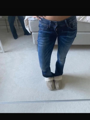 Blå lågmidjade bootcut jeans från G-Star RAW - Säljer ett par snygga blå jeans från G-Star RAW med bootcut passform. Jeansen har låg midja, fyra fickor och coola slitningar framtill. Lågmidjade jeans från raw, inner bens längd 76cm, bra skick💕