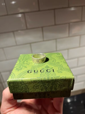 Gucci ghost ring  - Bilderna visar en silverring från Gucci, placerad på en grön Gucci-box med mönster. 925 stämpel i. Byten funkar 