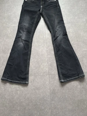 Svarta bootcut jeans från Gina Tricot - Säljer ett par svarta jeans från Gina Tricot i storlek 158. Byxorna har vita kontrastsömmar, broderade bakfickor och bootcut-ben. Klassisk femficksmodell med knapp och dragkedja framtill. Perfekta för dig som gillar en retrovibe! Jeans har använts 1 gång men finns inga synliga spår av användning.