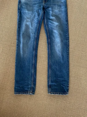 Nudie Jeans - Blåa Nudie Jeans i riktigt bra skick. Snygga fades och storlek 28/30, knappen är lite lös men annars är det inga defekter. Ställ gärna frågor!