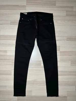 Levi's 510 svarta skinny jeans W33 L32 - Svarta Levi's 510 skinny jeans med klassisk femficksdesign och smal passform hela vägen ner. Jeansen har en snygg taperad siluett och är tillverkade i stretchig bomullsdenim för extra komfort. Perfekta om du gillar en tight look och vill ha ett par stilrena jeans.