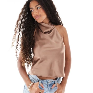 Champagnefärgad omlott linnetopp - Säljer en champagnefärgad omlott linnetopp i satin med halterneck och öppen rygg. Toppen har en croppad passform och ett elegant fall över axlarna. Perfekt att styla med jeans eller kjol för en trendig look. oanvänd 🤎 kan såklart skicka egna bilder vid önskemål. Storlek M men passar även s, jag har vanligtvis xs så lite stor på mig tyvärr, men superfin topp!