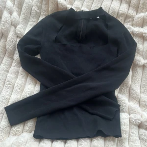 Svart topp från Zara - Svart stickad polotröja från Zara med lång ärm och cool half zip-detalj vid halsen. Tröjan har en modern, slim passform och är perfekt för dig som gillar stilrena och minimalistiska plagg. Materialet är mjukt och stretchigt, vilket gör den skön att bära. Liten defekt se bild 2
