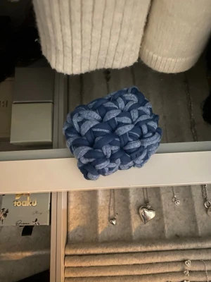 Blå handgjord virkat AirPods fodral - Säljer ett litet, handgjordt airpodsfodral i blått och ljusblått. Den är stickad i tjockt garn från rester av t-SHIRT massaindustrin och har en cool, flätad look. Perfekt för att förvara dina AirPods Pro 2 snyggt (sitter tajt för att säkra att de inte åker ut). Superunik och söt accessoar att smycka de med!