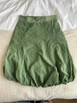 Grön manchesterkjol från Noa Noa - Säljer en grön manchesterkjol från Noa Noa by 21 Wales i storlek M. Kjolen har en ballongformad siluett, bred midja med broderade detaljer och dragkedja i sidan. Perfekt för dig som vill ha en unik och snygg kjol med cool struktur.