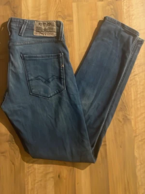 Replay Anbass blå jeans slim fit - Hej! Säljer ett par Replay Anbass jeans i klassisk blå tvätt. Jeansen har slim fit passform, fem fickor och snygga detaljer som Replay-logga på myntfickan. Materialet är mjukt jeans-tyg med lätt slitning för en cool look. Storleken är 29/30