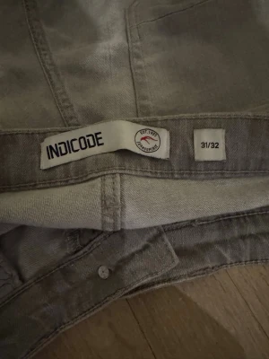 Grå slitna jeans från INDICODE - Säljer ett par grå jeans från INDICODE i storlek 31/32. Jeansen har slim/straight passform, slitna detaljer framtill och klassisk femficksdesign. Materialet är jeans och färgen är ljusgrå med lite tvättad look.