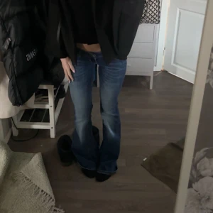 Blå bootcut jeans låg midja - Säljer ett par blå jeans med bootcut-modell och låg midja. Jeansen har klassisk femficksdesign och är tillverkade i ett mjukt denimtyg. Snygg tvätt med lätt slitning och markerade sömmar. Perfekta för dig som gillar en retro vibe och vill ha ett par jeans som sticker ut. Jag är 160!