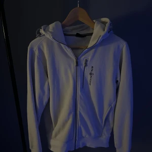 Sail racing hoodie - Snygg Vit hoodie från Sail Racing i storlek XS. Den perfekt nu när det blir lite kyligare och är väldigt stilren. Ny pris:1600kr och den är köpt ifrån sail racings hemsida. Mycket bra skick utan några skavanker i tyget