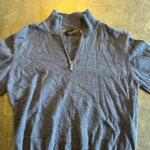 Blå stickad tröja med half zip från Sand - Nypris 1500kr.                                                    Mysig blå stickad tröja från Sand med halv dragkedja i halsen. Tröjan har lång ärm och en högre krage som ger en chill och stilren look. Perfekt för lager-på-lager och funkar året runt. Enkel att matcha med jeans eller chinos.