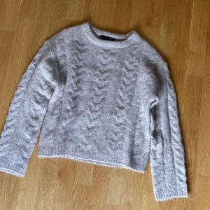 Beige stickad tröja - Supermysig rosa beige kabelstickad tröja från lager 157 i modellen ”boxy” med rund halsringning och ribbade muddar.  Den är stickad i ett mjukt material som känns skönt mot huden och har klassiska kabeldetaljer framtill och på ärmarna. Ljuset på bilderna jag tog blev dåligt, men tröjans färg i verkligheten liknar mer bilderna ifrån nättet än mina bilder. Har en svårare fläck på nackkragen (se sista bilden) men den syns knappt, speciellt inte om man har håret utskällt.  Storlek: XS. Nypris: 150kr
