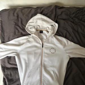 Vit hoodie från BOSS med dragkedja - Riktigt snygg boss hoodie, något år gammal men fortfarande väldigt skön. Hoodien har ett litet hål vid luvan .