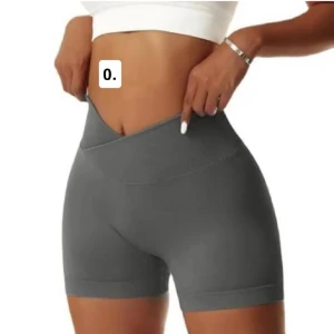 Grå höga träningstights shorts - Snygga grå shorts med hög midja och tight passform, perfekta för gymmet eller yoga. De är tillverkade i ett stretchigt syntetmaterial som sitter skönt och formar kroppen. Midjan har en cool omlott-design som ger extra stilpoäng.